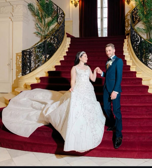groom wearing navy tuxedo rental standing with bride on red stairs