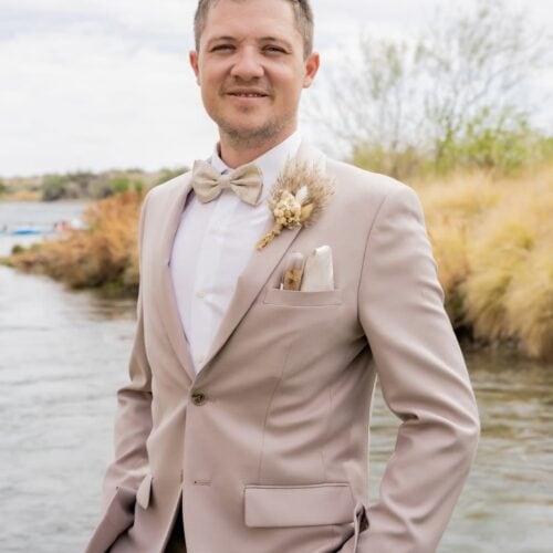Groom smiling wearing tan suit rental by NTR