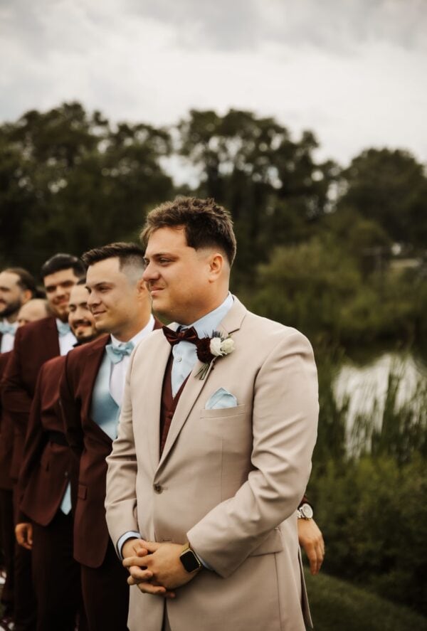 groom wearing tan suit rental with blue shirt and maroon accessories