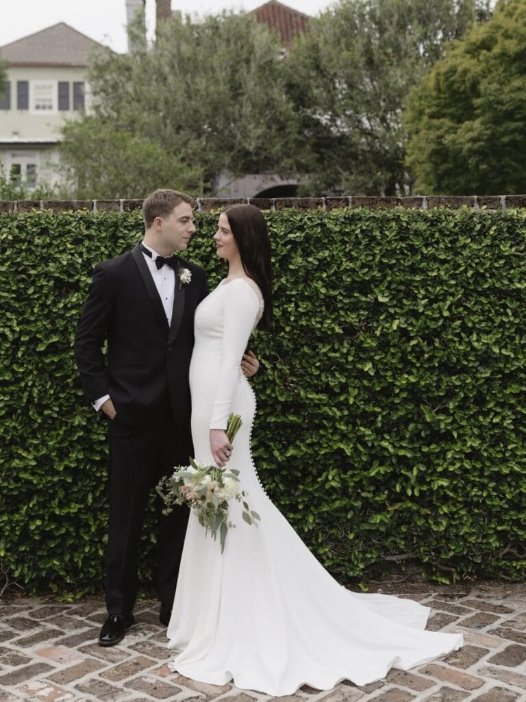 groom in black shawl tuxedo with bride outside