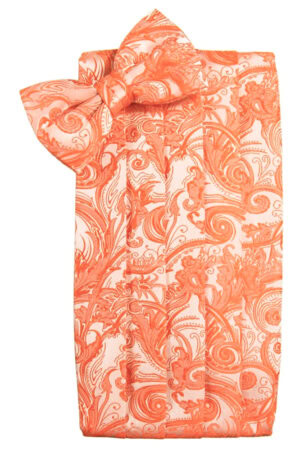 Orange and white paisley-patterned napkin folded with a bow on top, resembling a decorative gift wrap arrangement.