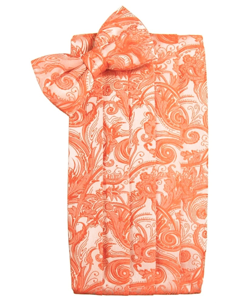 Orange and white paisley-patterned napkin folded with a bow on top, resembling a decorative gift wrap arrangement.