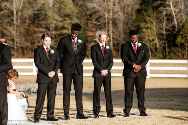 four groomsmen standing outside in tuxedo rentals