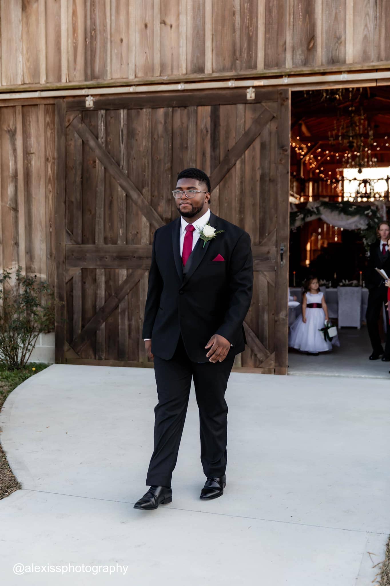 a groomsman wearing a black tuxedo rental walking down the aisle at wedding