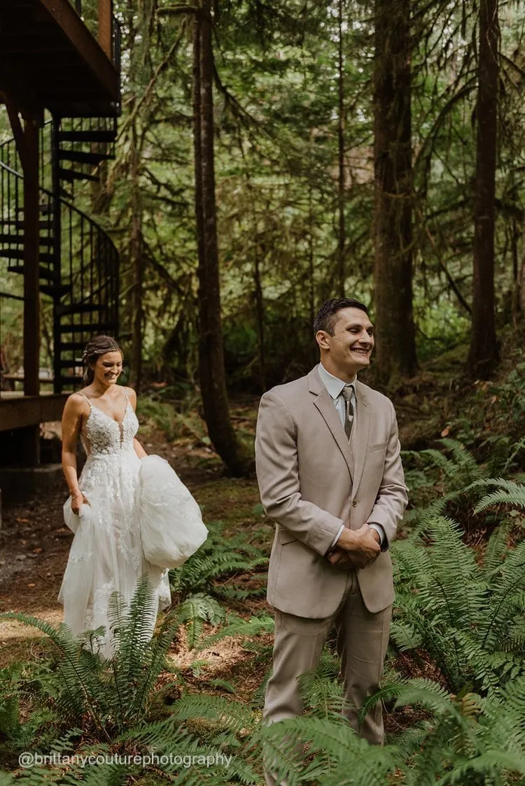 a bride in her wedding dress approaching the groom from behind before their first look