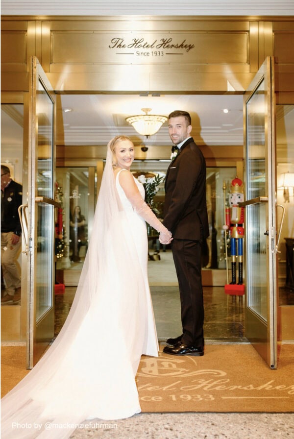 wedding couple dressed up standing in doorway holding hands and smiling