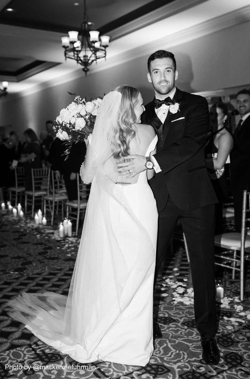 groom wearing a black tuxedo rental standing with bride at wedding