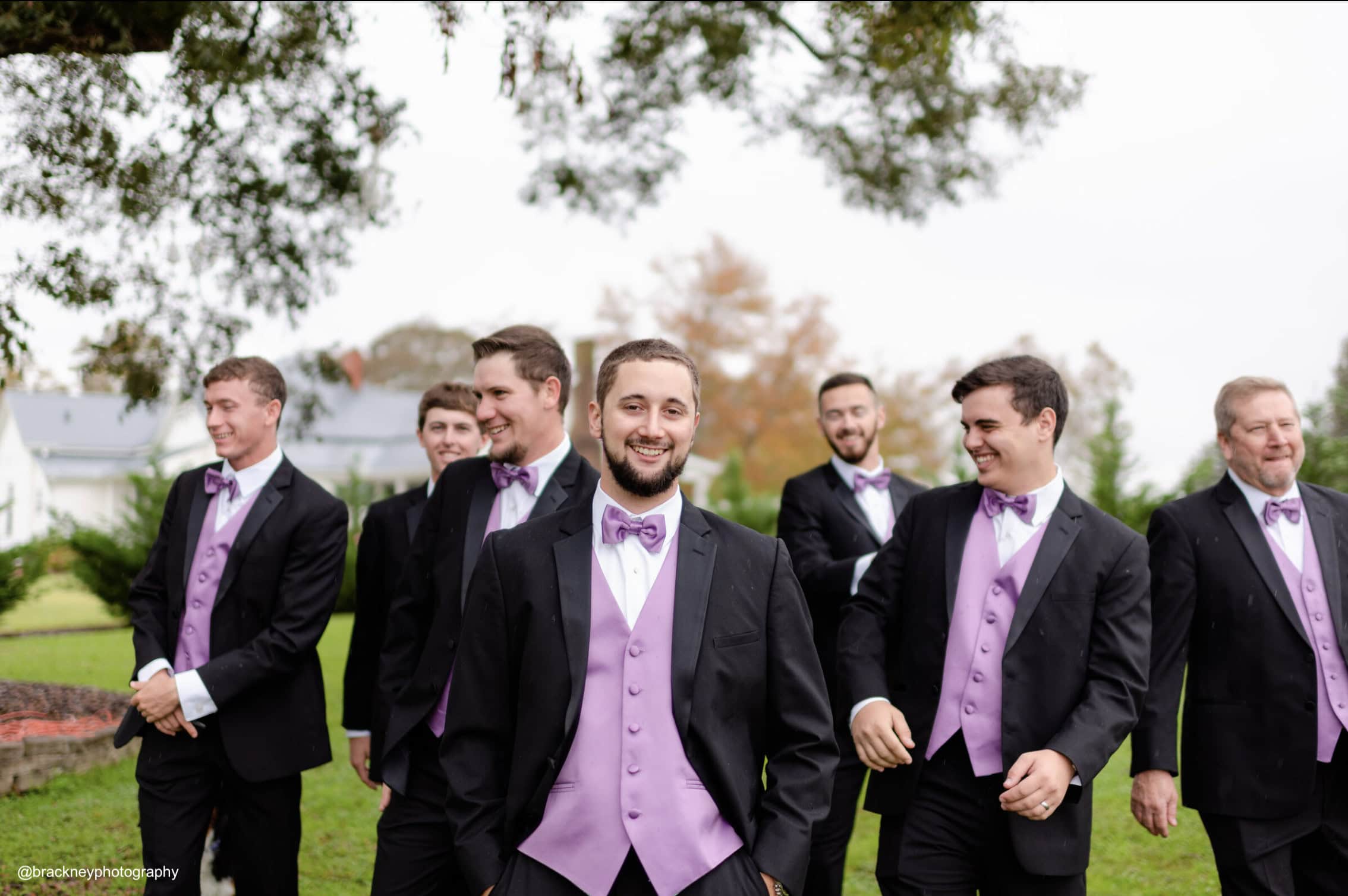 a groom and his groomsmen wearing black and purple tuxedo rentals before the wedding