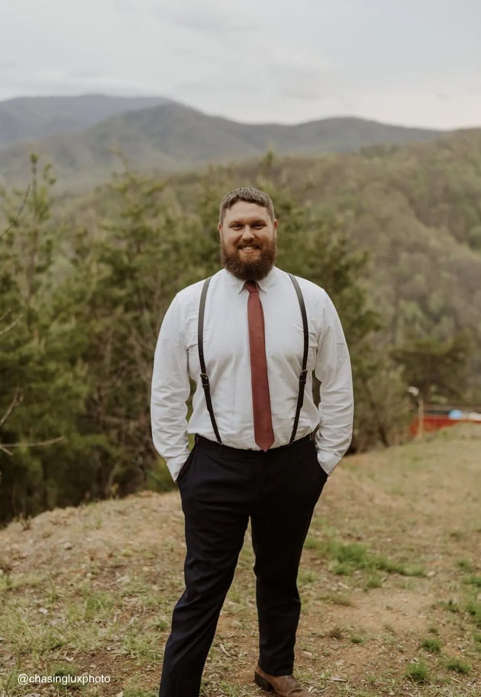 a groom wearing a coatless tuxedo rental in front of mountain view