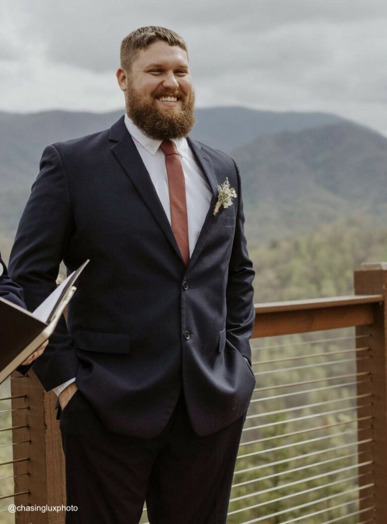 a groom wearing a navy suit rental by national tuxedo rentals smiling