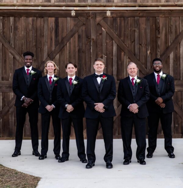 groom and his groomsmen standing outside of a barn