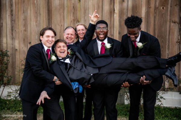 groomsmen holding groom wearing a black tuxedo rental