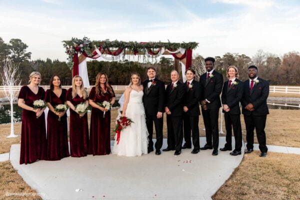 groom and groomsmen in tuxedo rentals at an outdoor wedding ceremony with bridal party