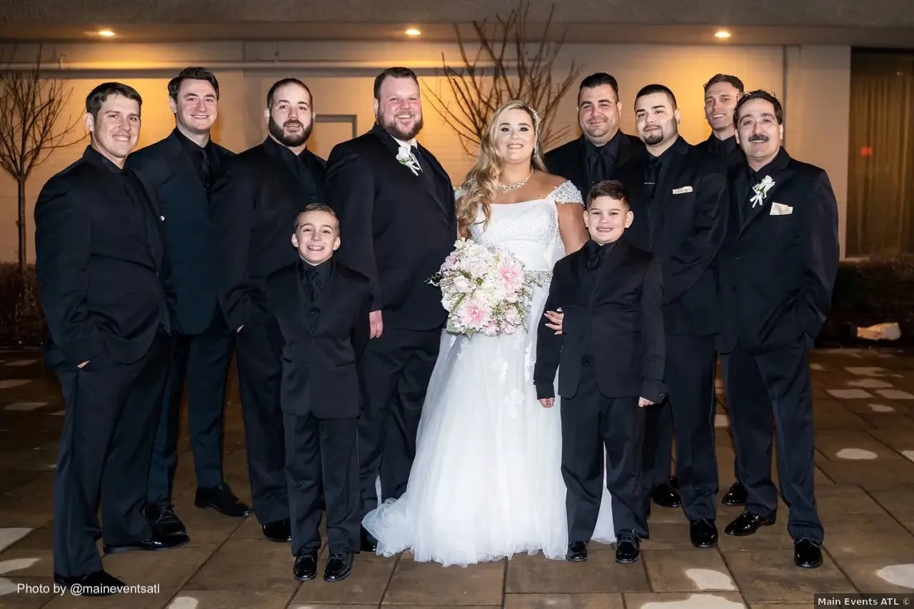 wedding photo of bride and groomsmen wearing black tuxedo rentals