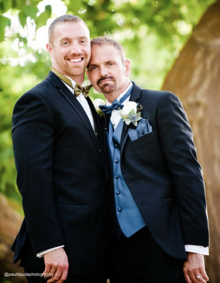 two men wearing black tuxedo rentals outside