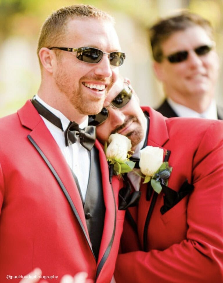 two men wearing matching red tuxedo rentals for their outdoor wedding