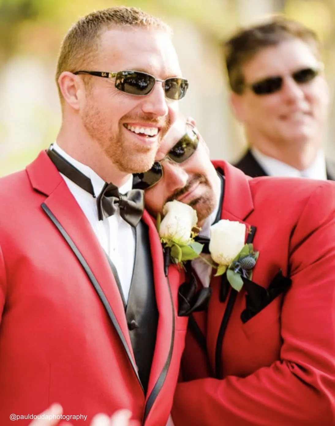 two men wearing matching red tuxedo rentals for their outdoor wedding