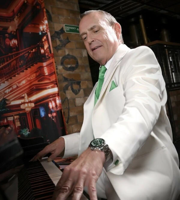 man playing piano wearing ivory tuxedo rental