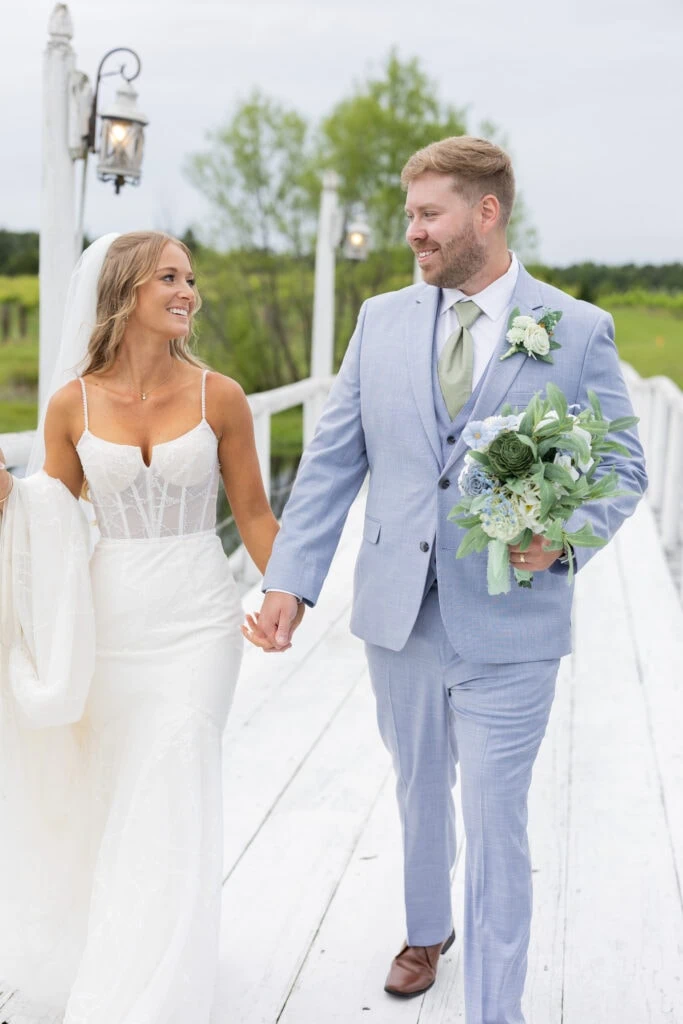 bride and groom walking on white bridge