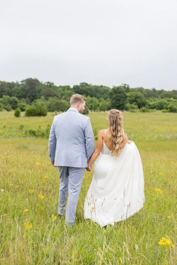 BC90C19E-77C8-44F7-9DC2-2B196779527D | National Tuxedo Rentals bride and groom walking in green field