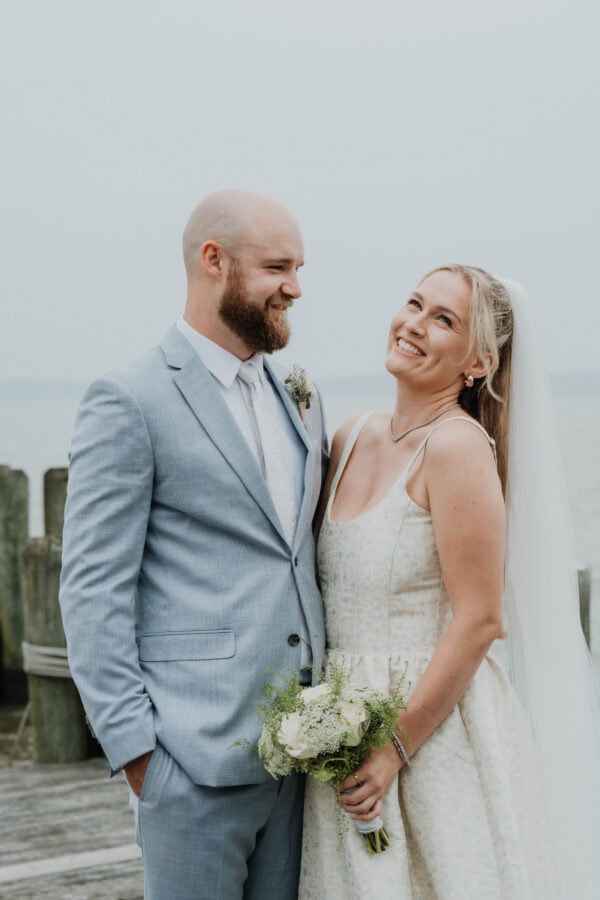 Groom wearing oxford blue suit rental standing with bride