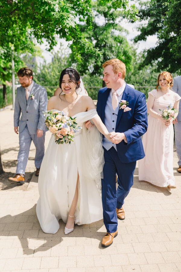 bride and groom walking with wedding party outside