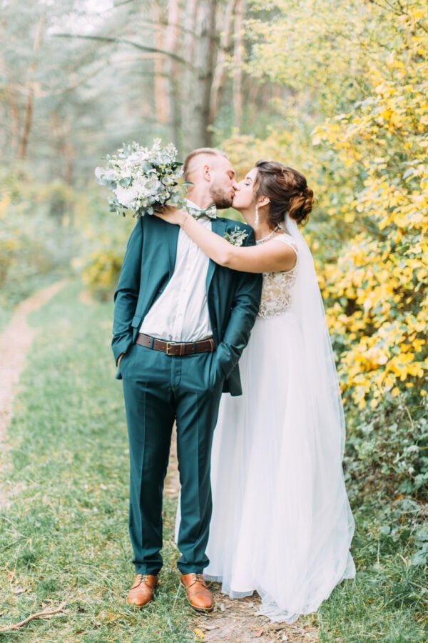 man in green suit rental kissing bride after wedding