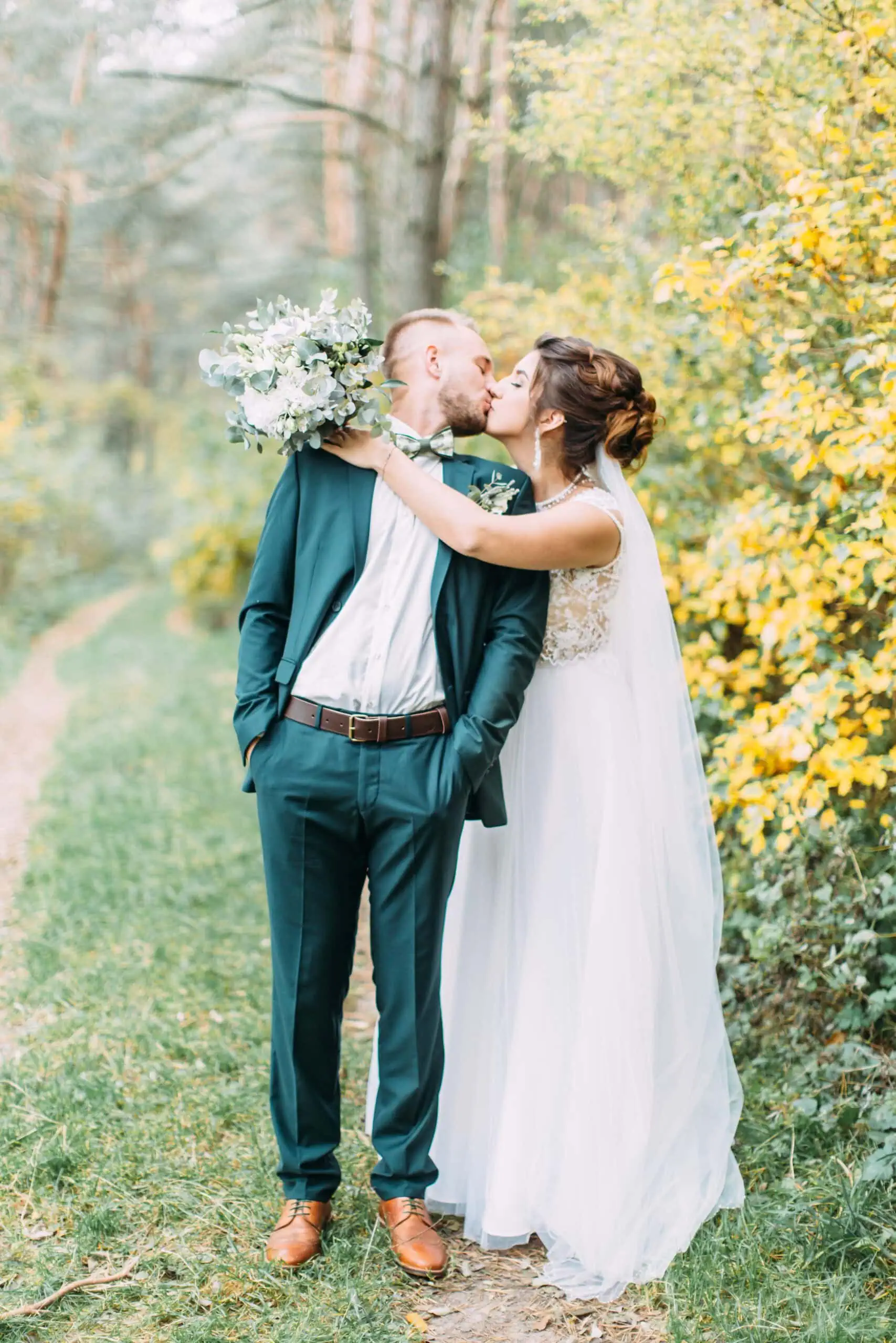 KissesAndHugsOfLoversInNature man in green suit rental kissing bride after wedding