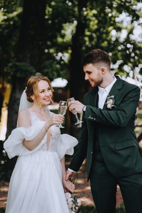groom in green suit rental drinking champagne with bride