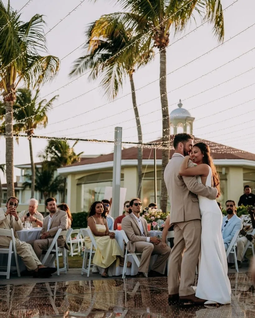 groom wearing tan suit rental dancing with bride at reception outdoors