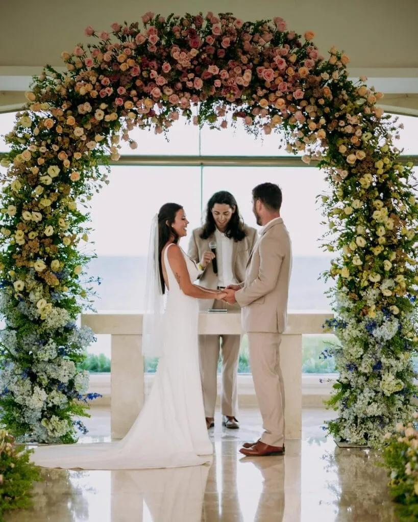 groom wearing tan suit marrying bride at ceremony