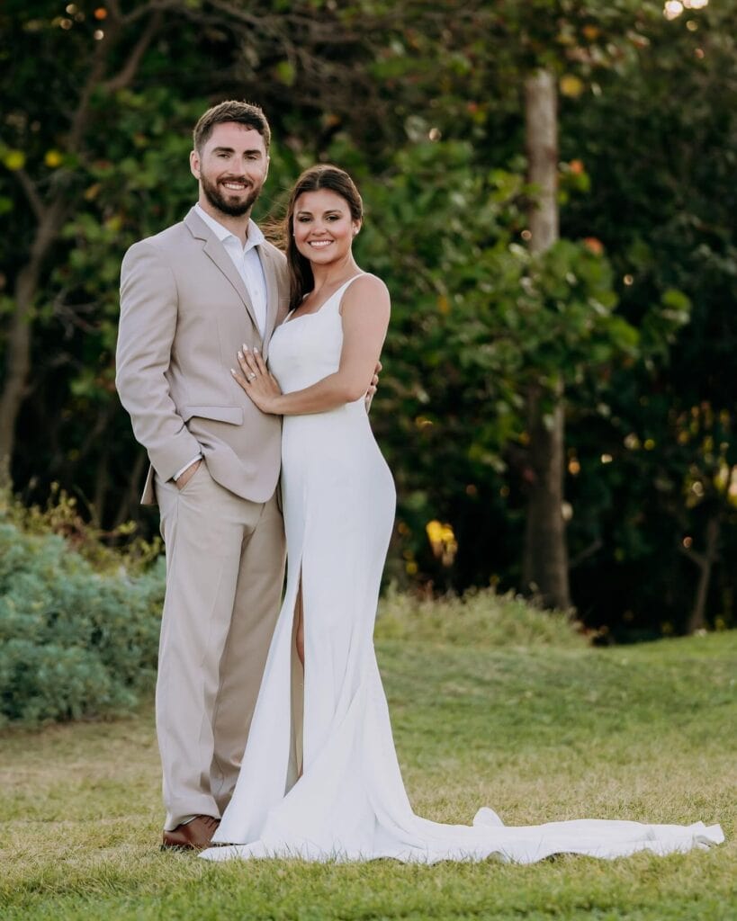 groom wearing tan suit standing with bride outdoors