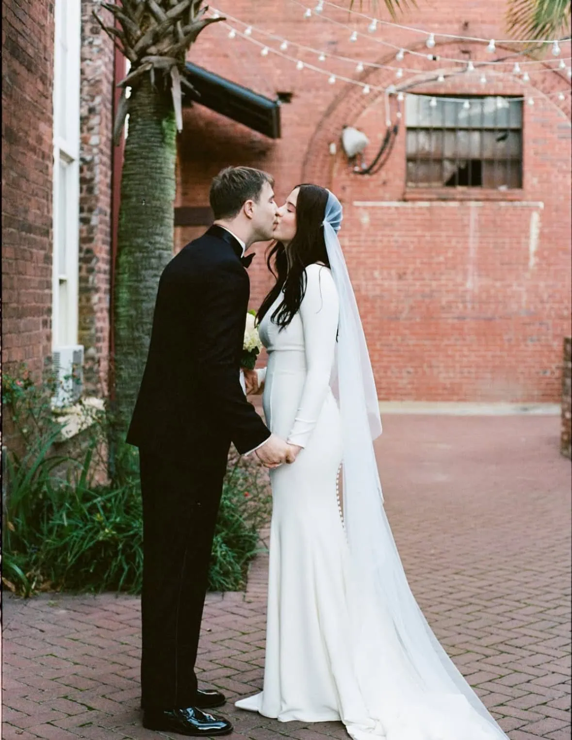 bride and groom in front of red building