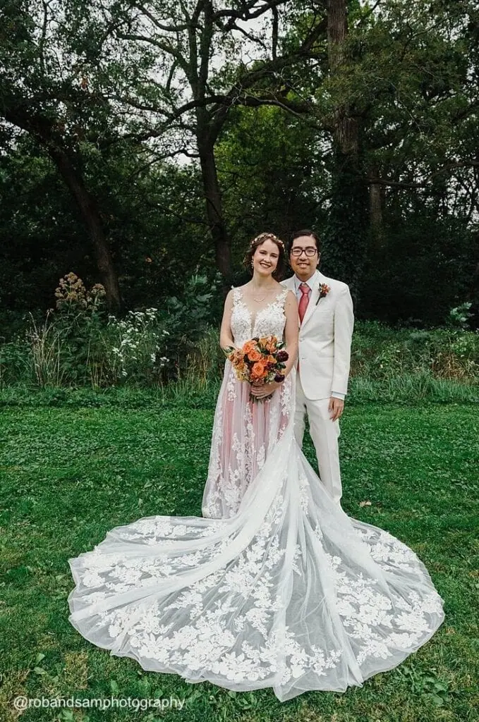 groom wearing a white tuxedo rental smiling with bride