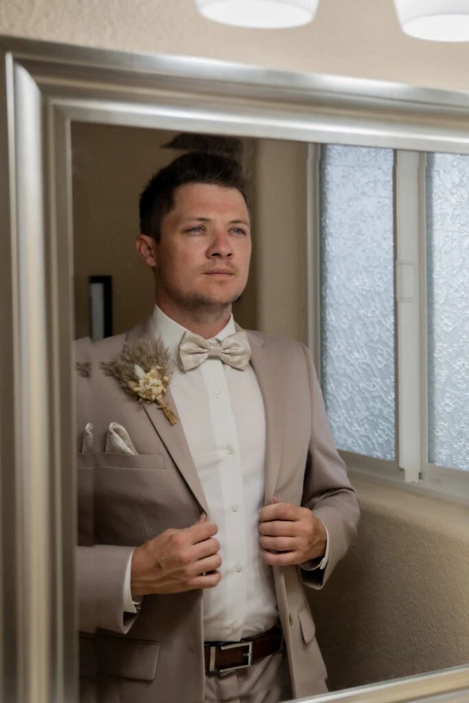 man in tan suit rental looking in mirror