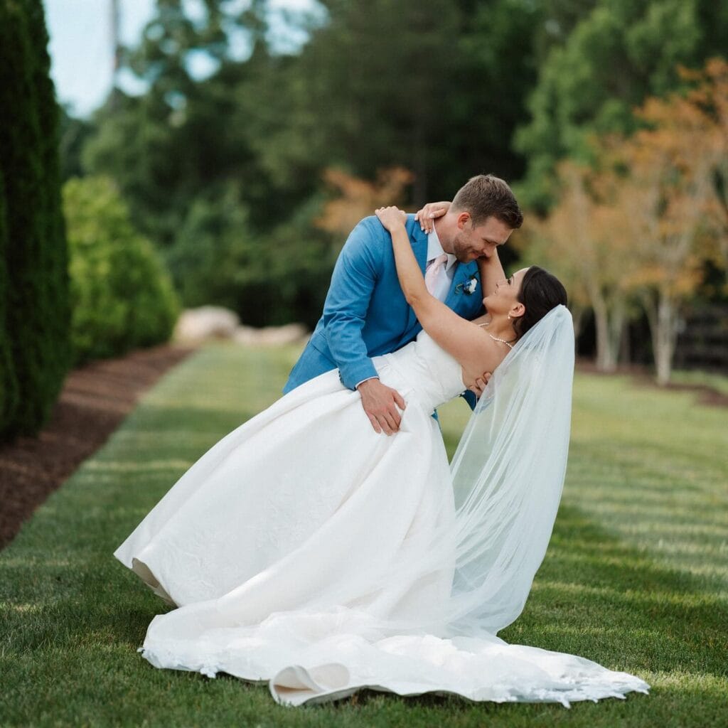 groom wearing marine blue suit rental kissing bride after wedding