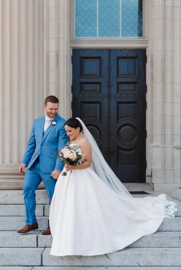 groom wearing marine blue suit rental walking down stairs with bride