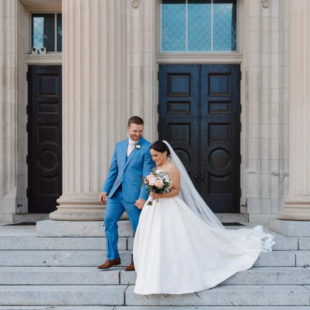 groom wearing marine blue suit rental walking down stairs with bride