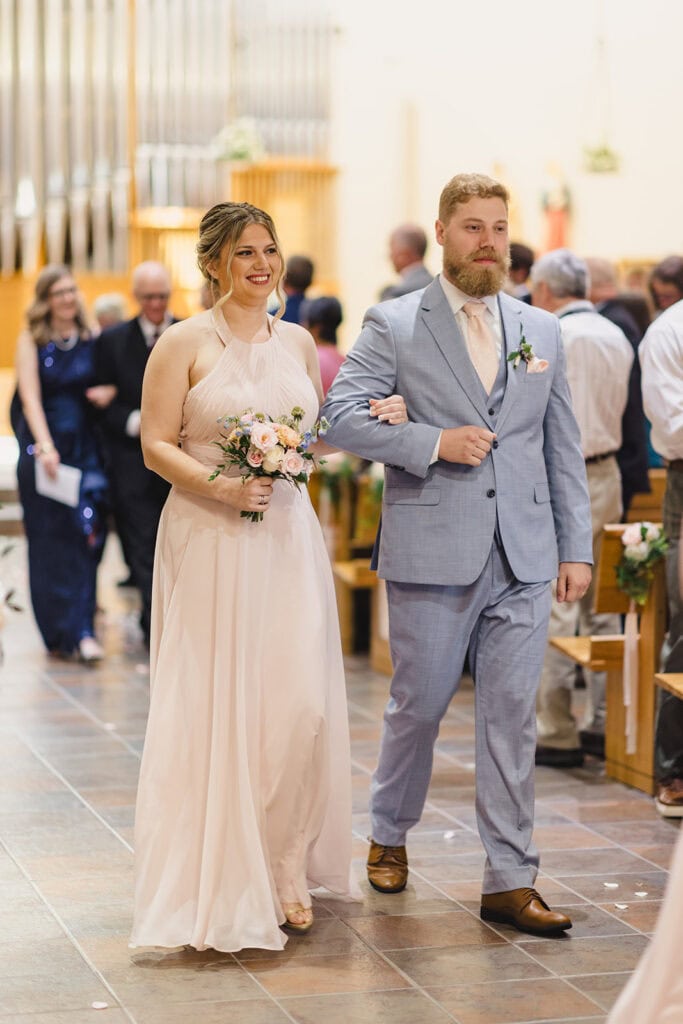 groomsmen walking with bridesmaid down the aisle
