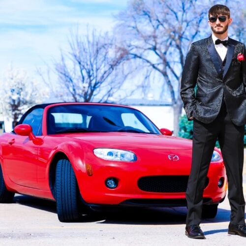 Black-Paisley-Tuxedo-Real-Customer | National Tuxedo Rentals Young man wearing a black tuxedo next to his car