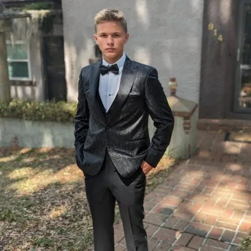 Young man in black paisley tuxedo rental