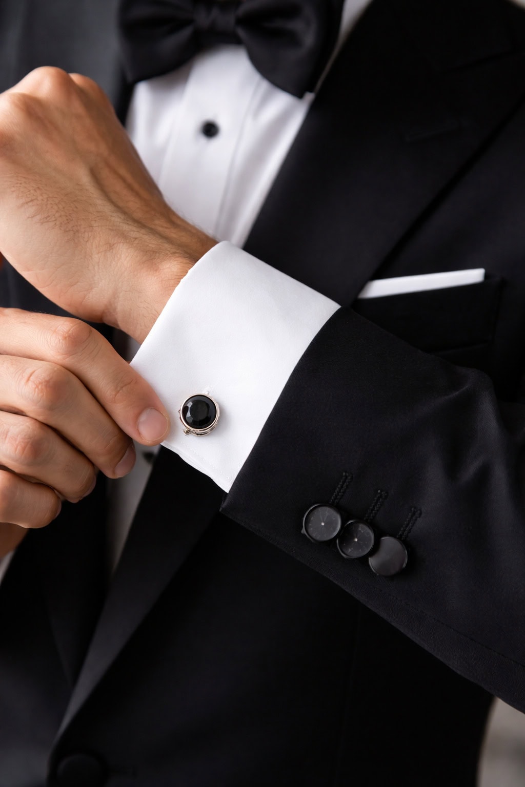 man wearing black tuxedo cufflinks
