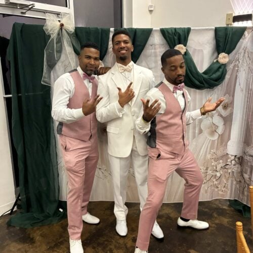 groom in ivory tuxedo standing with groomsmen in pink suits