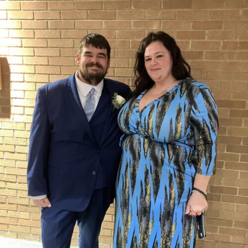 man wearing navy suit posing with date