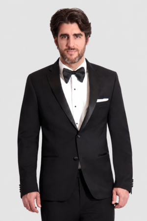 Man wearing a black tuxedo with bow tie and white pocket square, posing against a light background.