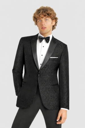 Man wearing a black patterned tuxedo with satin lapels, white dress shirt, black bow tie, and pocket square.