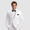 Man in a white tuxedo with a black bow tie and pocket square, smiling confidently against a light background.